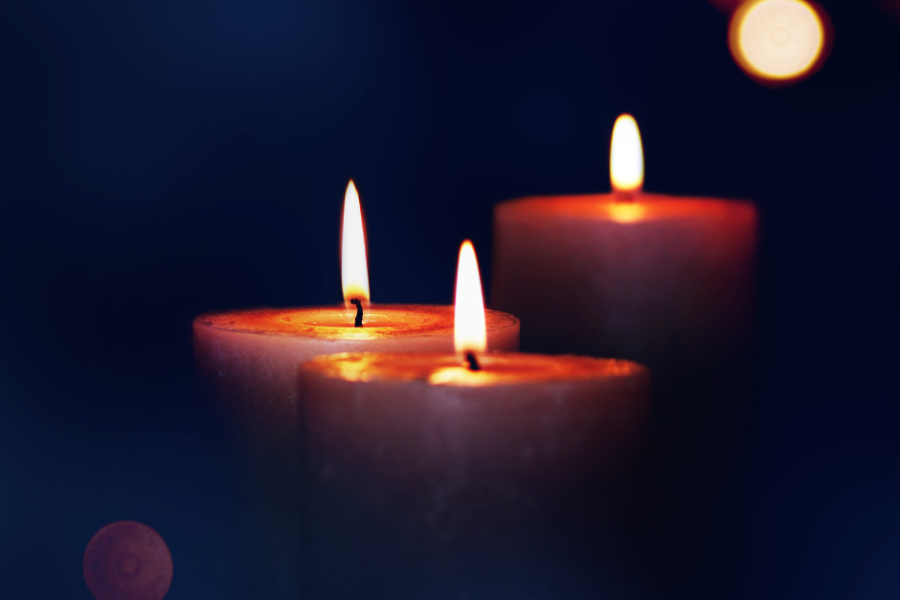 Three lit pillar candles against a black background